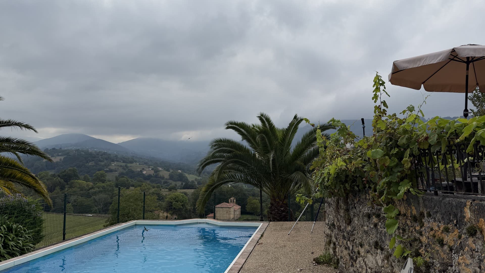 Clouds roll in over the mountains behind a swimming pool in northern Spain